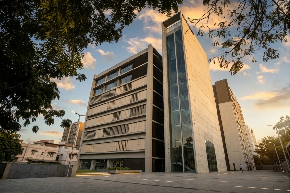 Meghmani Corporate House in Prahladnagar, Ahmedabad, with its glass-fronted tower and forecourt in warm evening light.